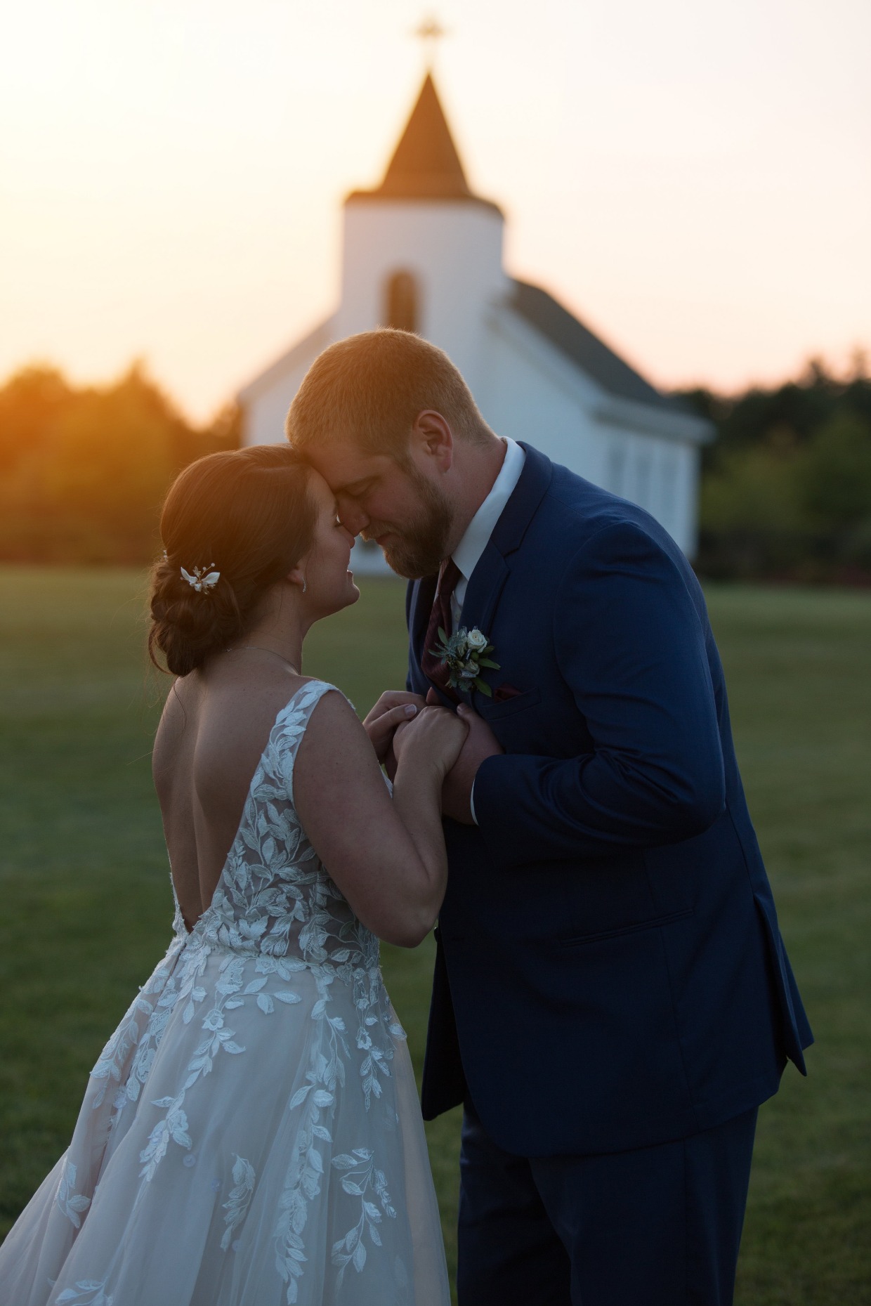 couple in sunset in front of white wedding chapel