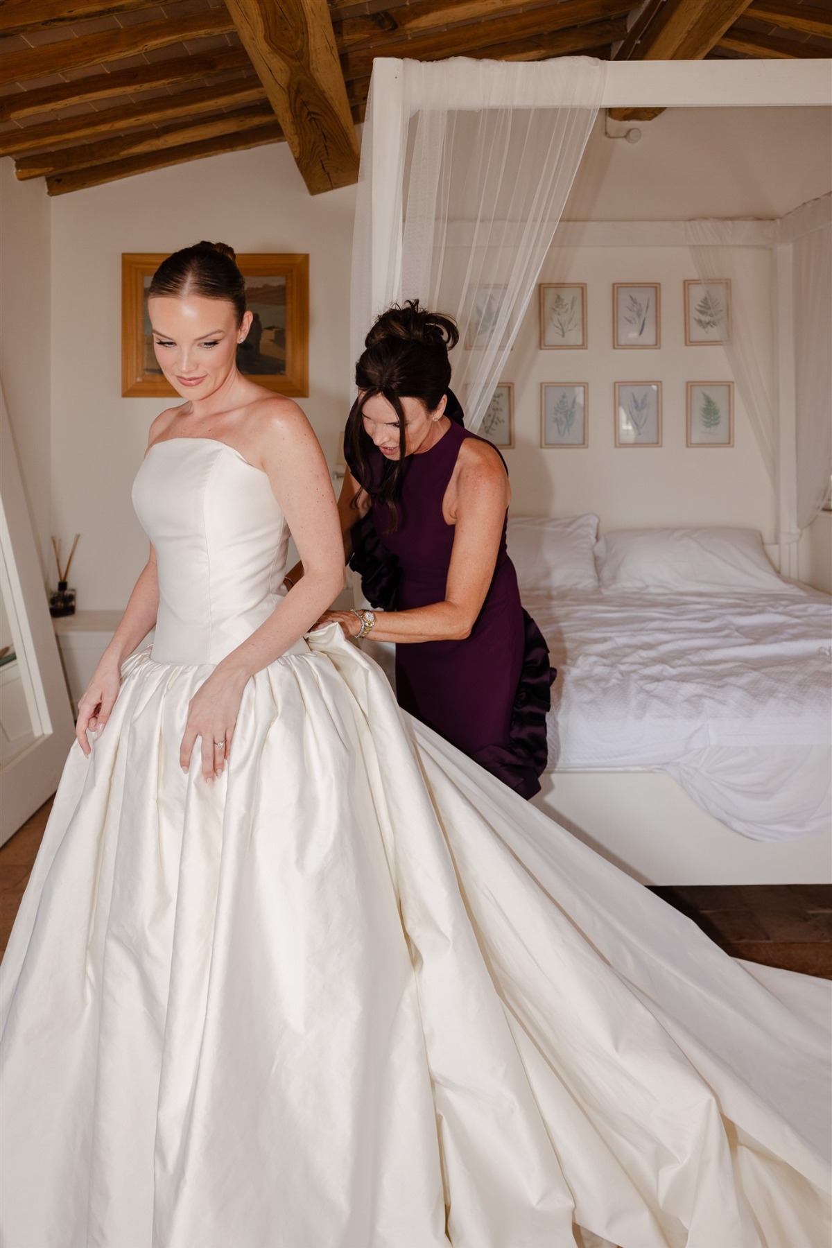 mom helping bride into dress