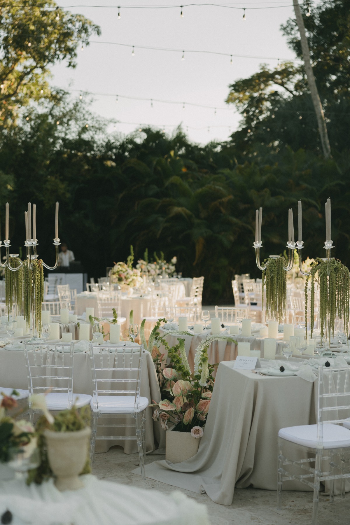 super whimsical wedding reception during sunset with draped ivory table clothes and lots of whimsical handing florals and candles