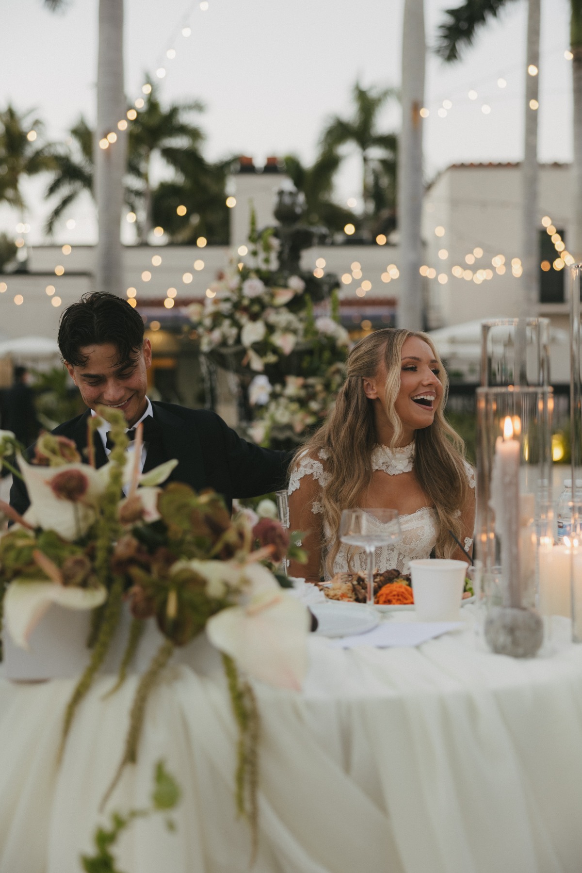 slavic bride and groom at sweetheart table with candles and twinkle lights all around and looking very happy