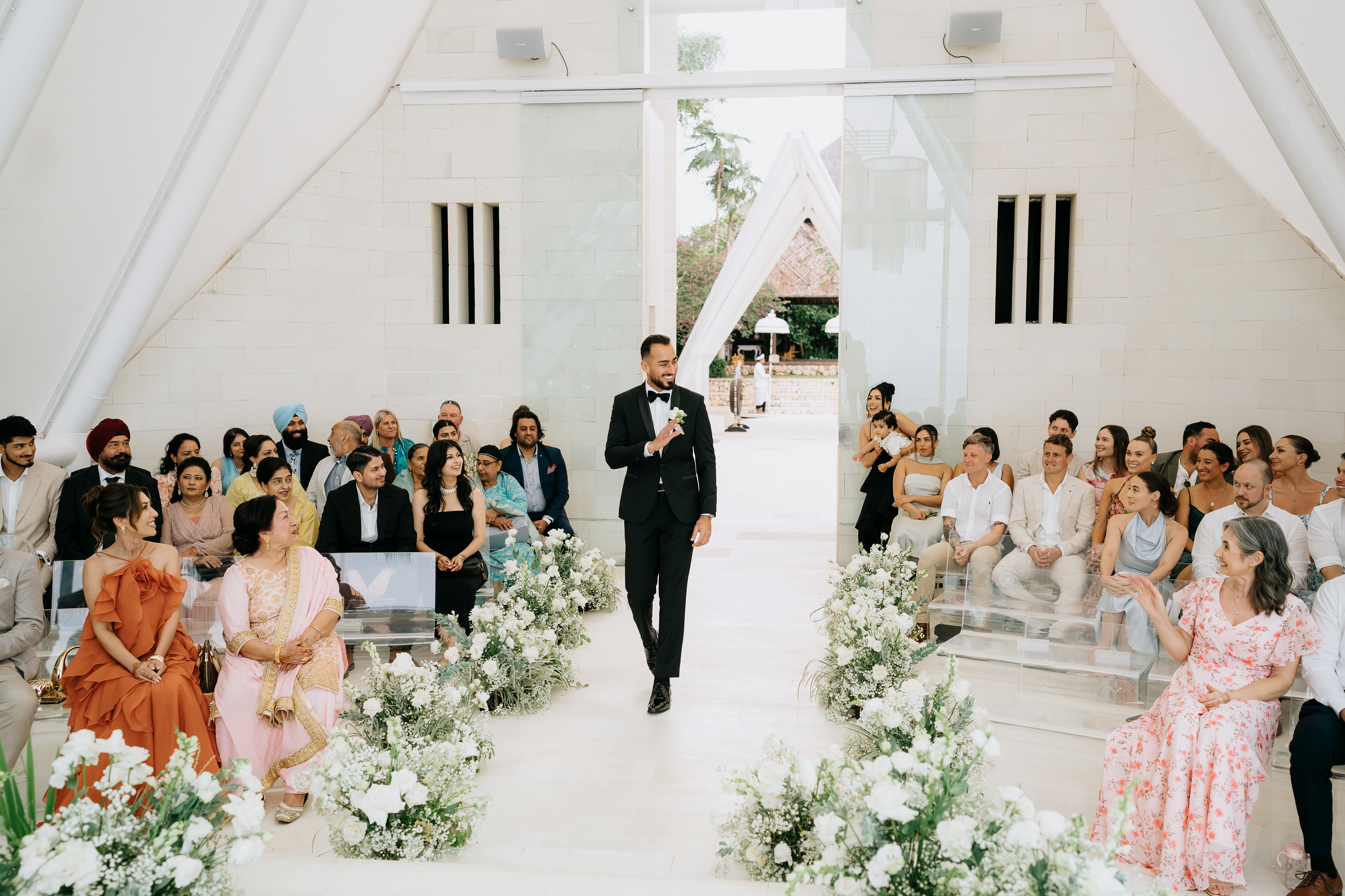 groom walking down white aisle