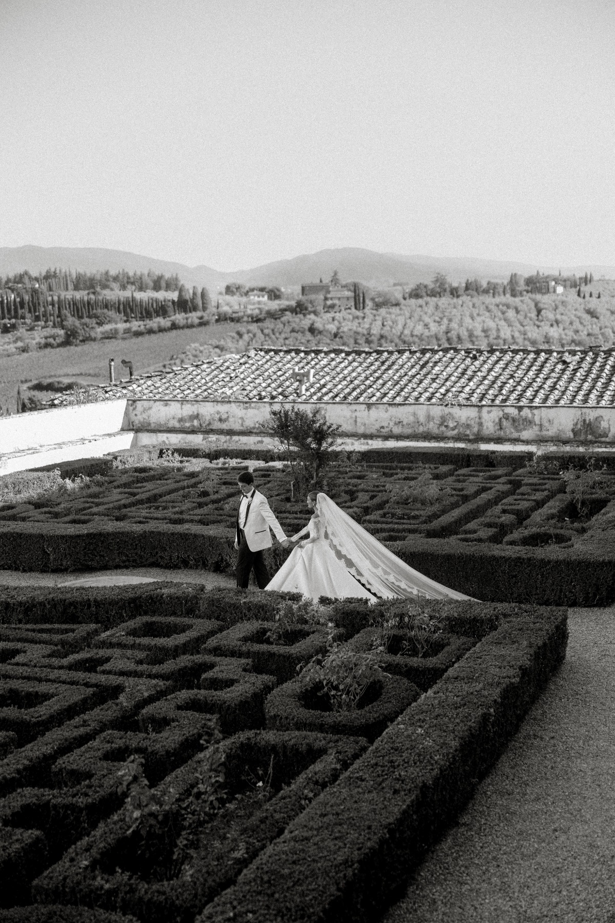 black and white photo of wedding couple walking through italian gardens