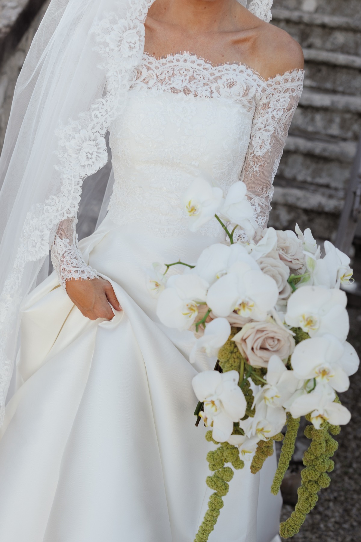 close up of bride's long sleeve wedding dress with orchid bouquet 