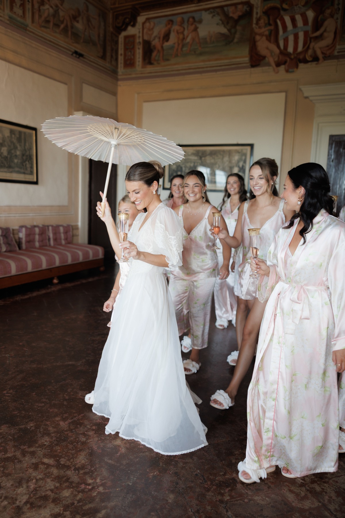 bride and her bridesmaids holding champange and wearing silk robes and pjs