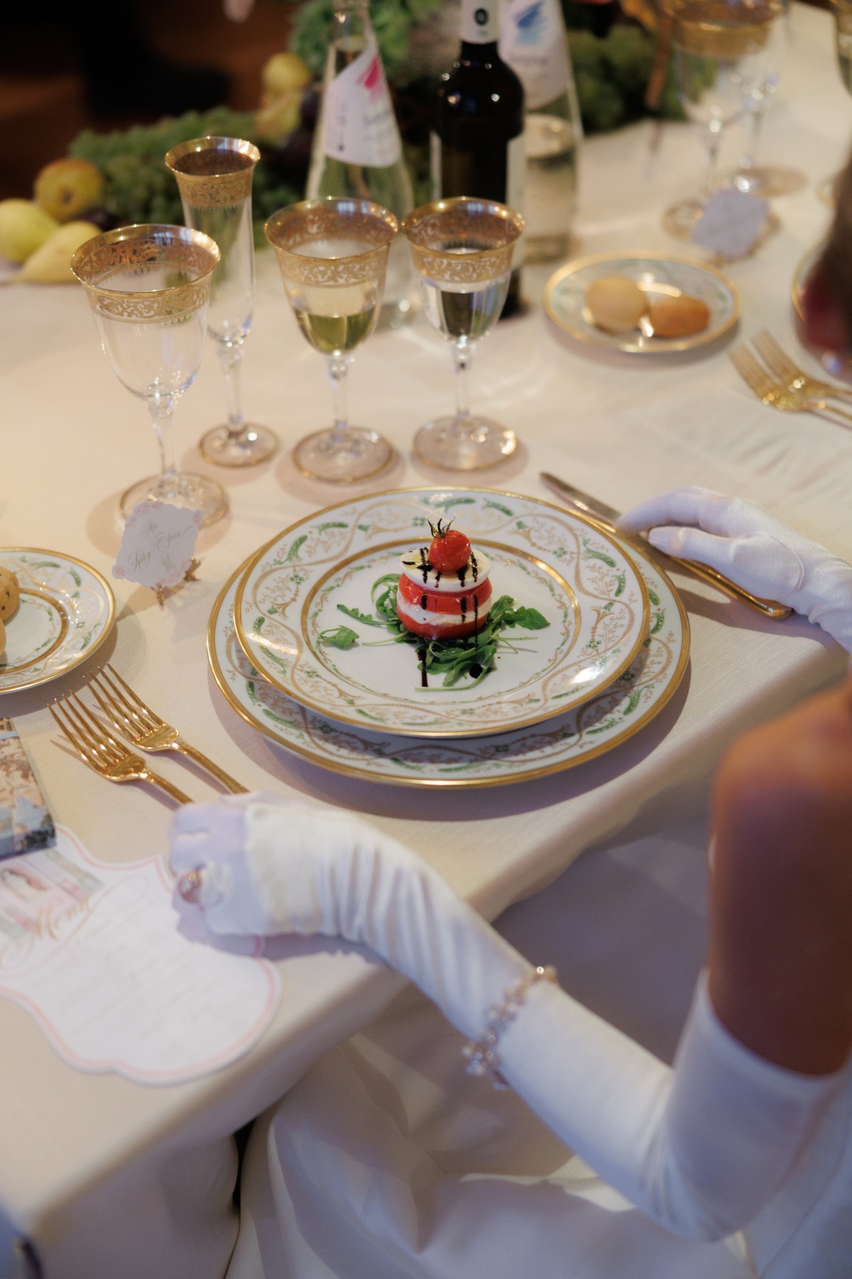bride with white gloves sitting and about to eat her caprese 