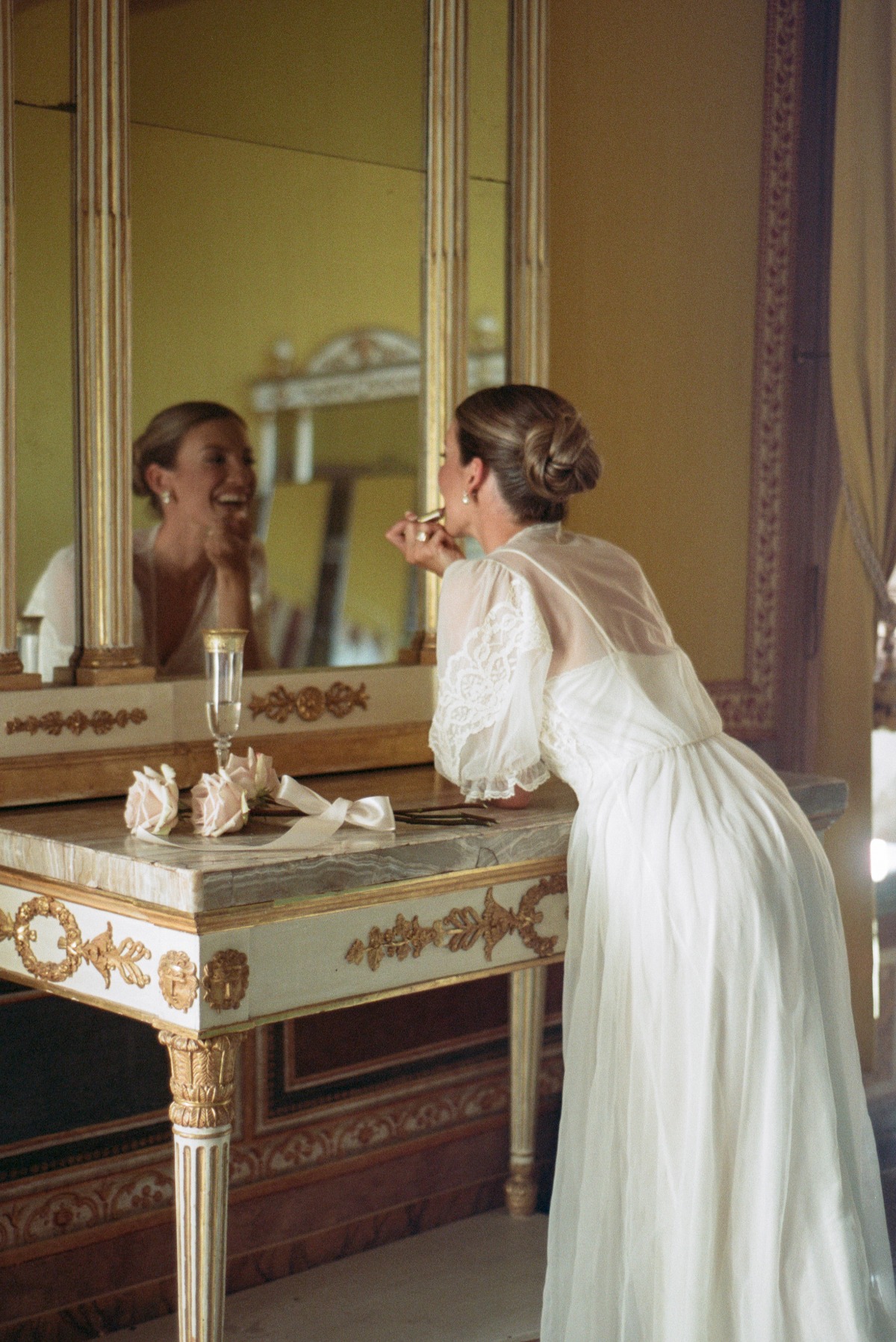 bride in robe putting on lipstick in mirror