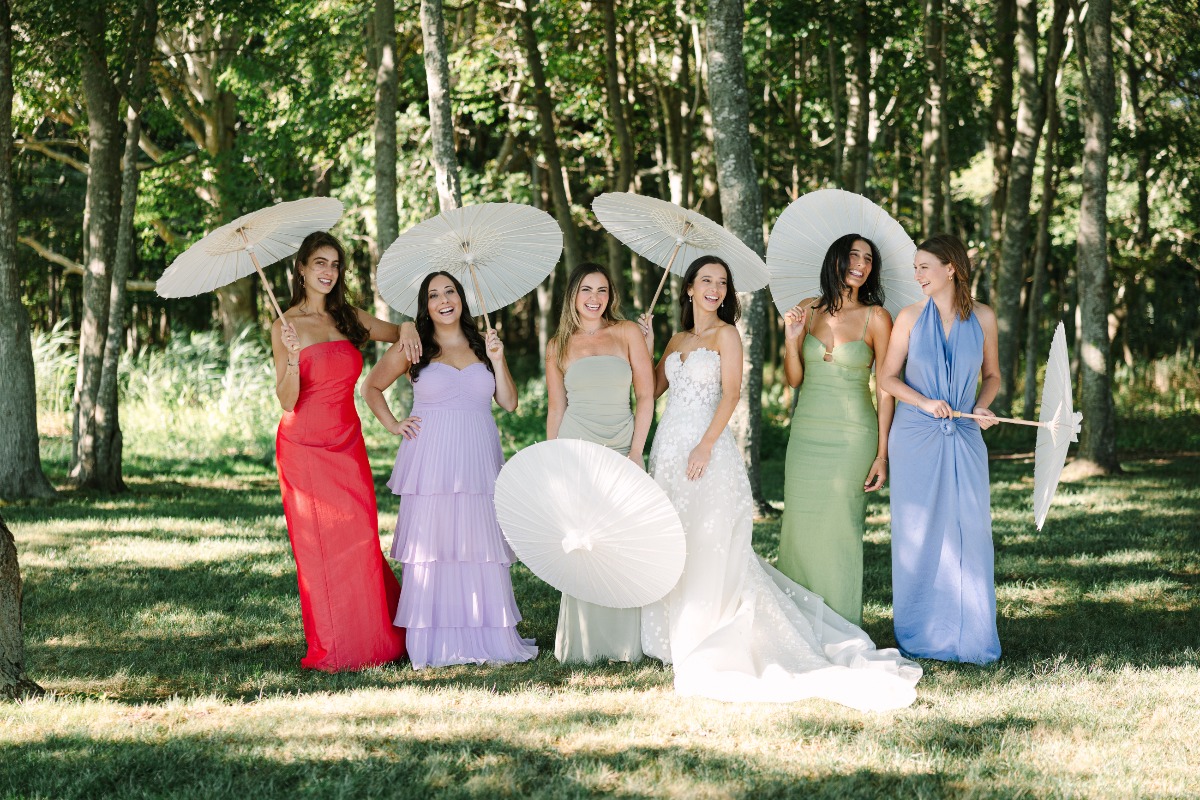 bridesmaids outside in different colored dresses holding white umbrellas