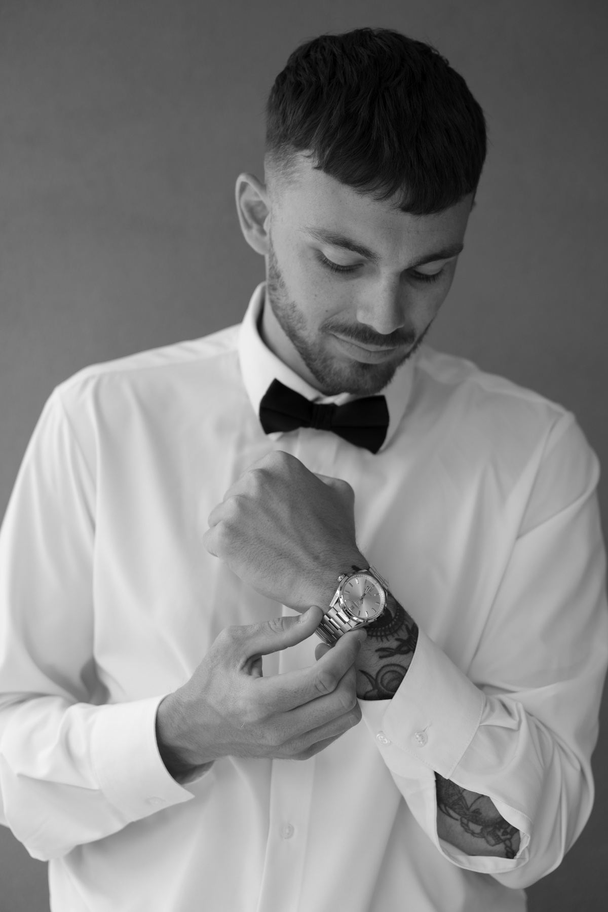 black and white photo of groom getting ready and securing watch